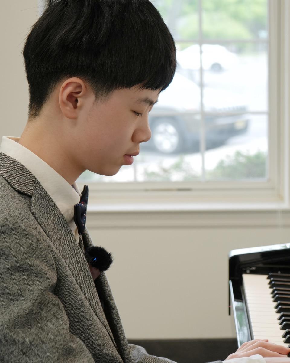 A student in concert dress at the piano during a lesson