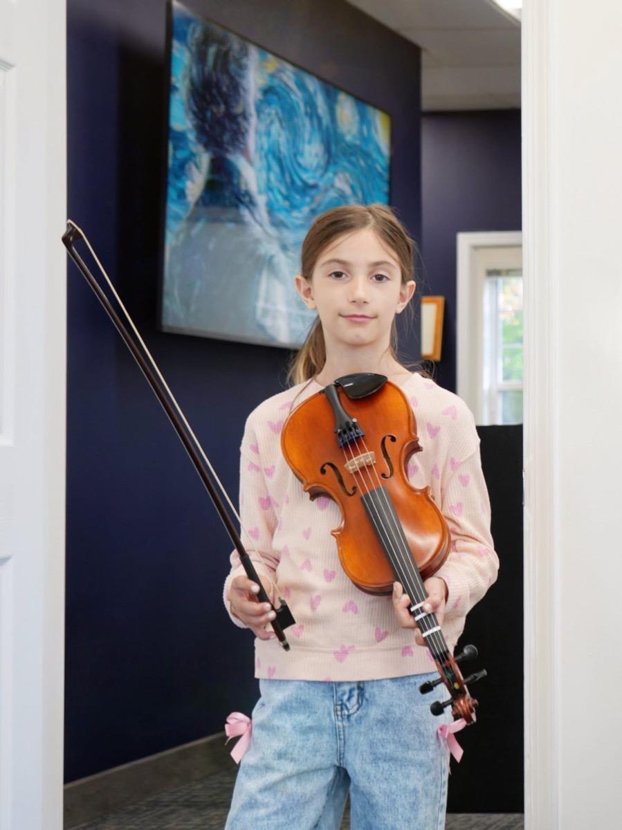 A young violinist holding her instrument in the Princeton studio