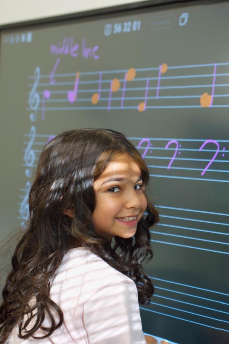A student at the illuminated staff board during a music theory lesson